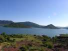 Photo d'un lac, sur terre volcanique rouge et ciel bleu